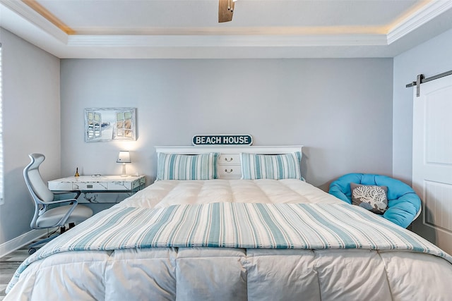 bedroom featuring crown molding, a tray ceiling, a barn door, and wood-type flooring