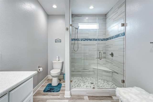 bathroom featuring vanity, wood-type flooring, toilet, and a shower with shower door