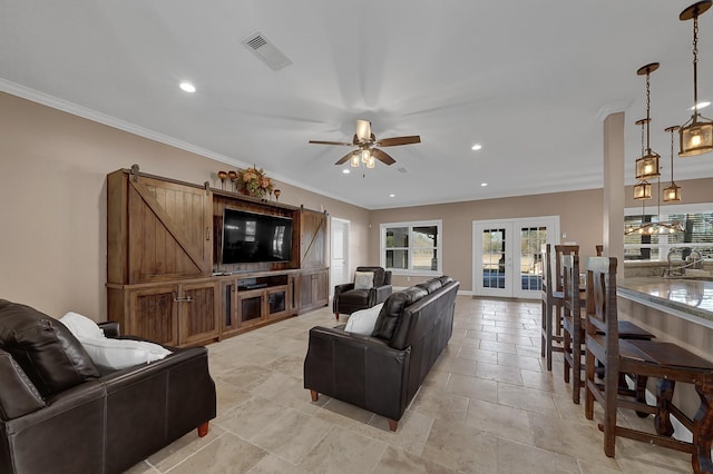 living room featuring french doors, ceiling fan, a barn door, and crown molding