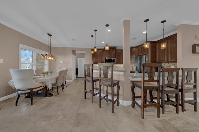 kitchen with appliances with stainless steel finishes, a breakfast bar, decorative light fixtures, tasteful backsplash, and dark brown cabinetry