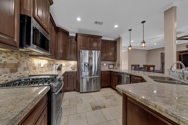 kitchen featuring sink, crown molding, hanging light fixtures, appliances with stainless steel finishes, and light stone countertops