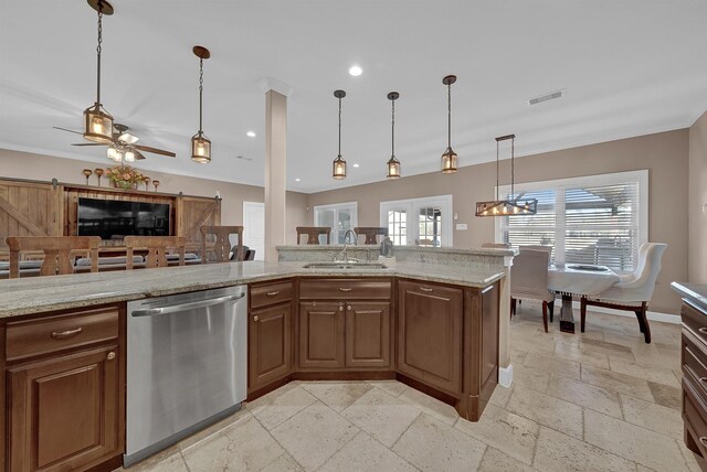 kitchen with light stone countertops, sink, stainless steel dishwasher, and decorative light fixtures