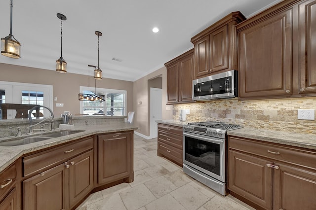 kitchen featuring sink, hanging light fixtures, stainless steel appliances, light stone counters, and tasteful backsplash