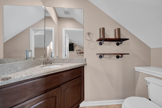 bathroom with vaulted ceiling, vanity, and toilet