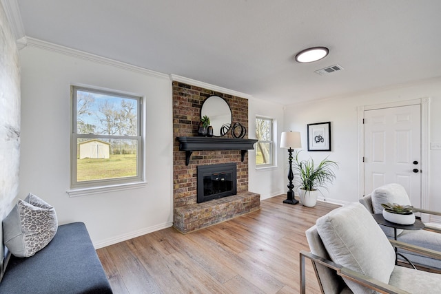 living room featuring crown molding, a brick fireplace, and light hardwood / wood-style flooring