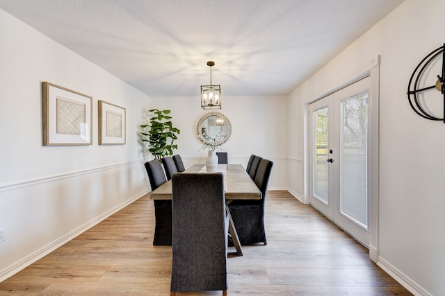 dining space featuring french doors, a notable chandelier, and light hardwood / wood-style flooring