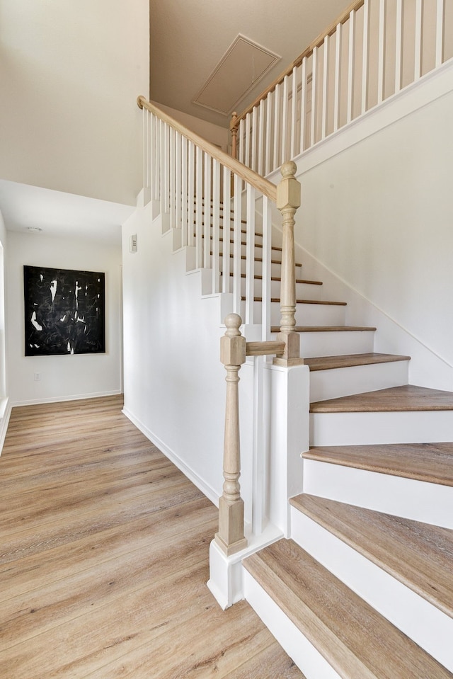 staircase featuring wood-type flooring and a high ceiling