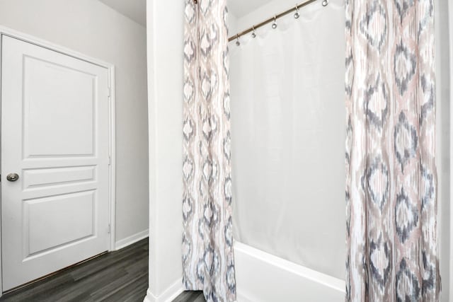 bathroom featuring wood-type flooring and shower / bath combo with shower curtain