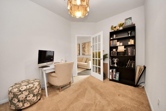 carpeted home office with a notable chandelier and french doors