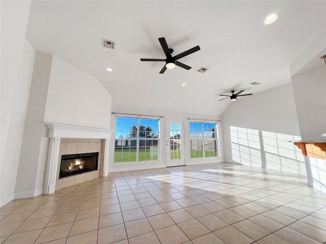 unfurnished living room featuring ceiling fan, lofted ceiling, a tiled fireplace, and light tile patterned floors