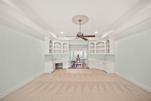 unfurnished living room with crown molding, built in desk, and light colored carpet