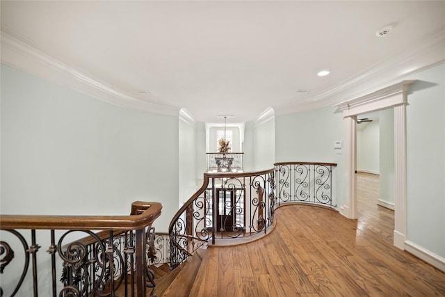 hallway with crown molding, wood-type flooring, and an inviting chandelier