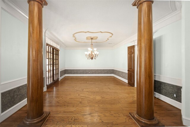 hallway featuring an inviting chandelier, crown molding, dark hardwood / wood-style floors, and ornate columns