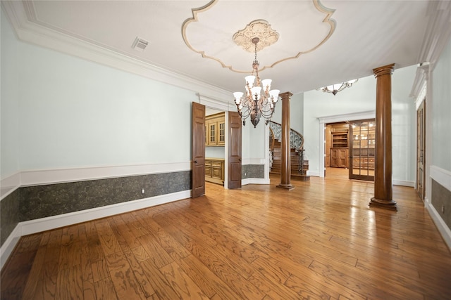 interior space with ornate columns, ornamental molding, an inviting chandelier, and light hardwood / wood-style floors