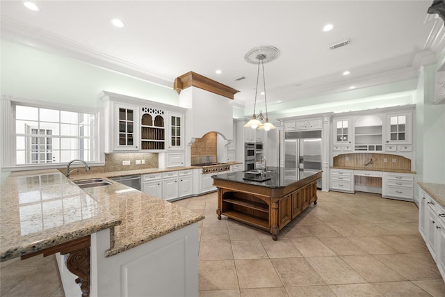 kitchen with sink, white cabinetry, hanging light fixtures, appliances with stainless steel finishes, and a kitchen island