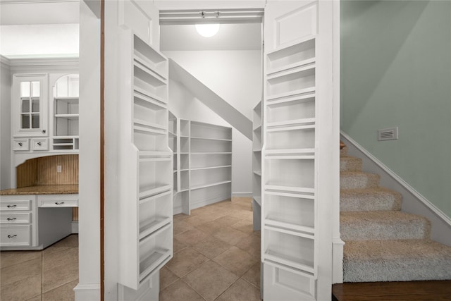 spacious closet featuring light tile patterned flooring and built in desk