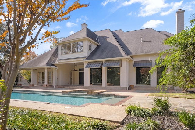 rear view of property with ceiling fan, a pool with hot tub, and a patio