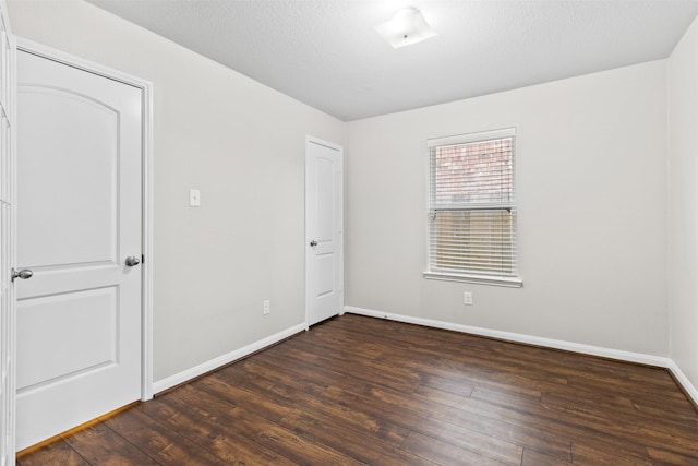 unfurnished room featuring a textured ceiling and dark hardwood / wood-style flooring