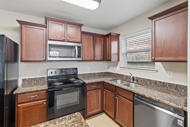 kitchen with sink, black appliances, dark stone counters, and light tile patterned flooring