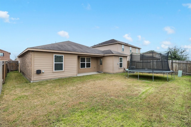 back of property with a trampoline and a lawn