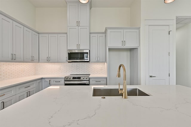 kitchen with light stone counters, sink, tasteful backsplash, and appliances with stainless steel finishes