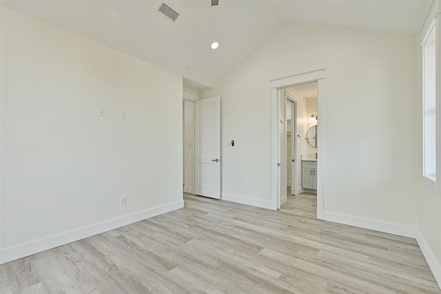 unfurnished bedroom featuring ensuite bathroom, lofted ceiling, and light hardwood / wood-style floors