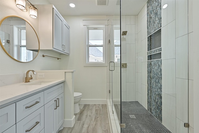 bathroom featuring an enclosed shower, vanity, a wealth of natural light, and toilet