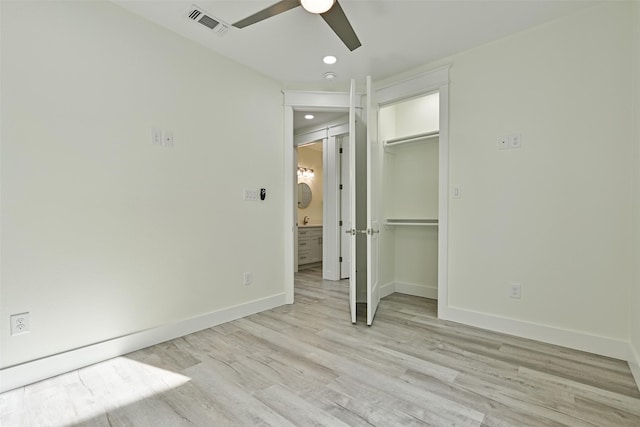 unfurnished bedroom with ceiling fan, a walk in closet, a closet, and light wood-type flooring