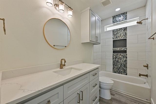 full bathroom featuring vanity, hardwood / wood-style flooring, toilet, and tiled shower / bath