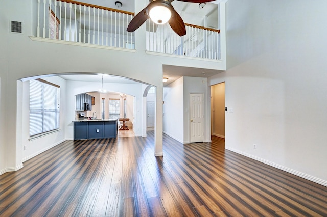 living room with dark hardwood / wood-style floors, ceiling fan, and a towering ceiling