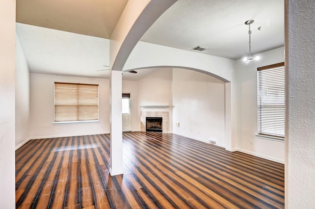 unfurnished living room featuring a tiled fireplace and dark hardwood / wood-style flooring