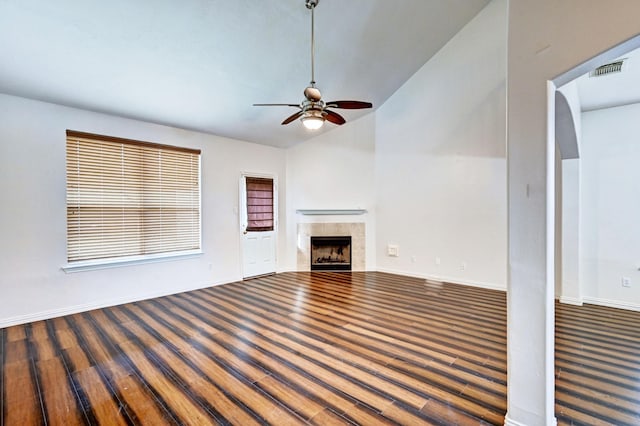 unfurnished living room featuring dark wood-type flooring, ceiling fan, lofted ceiling, and a fireplace