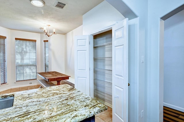 kitchen with light tile patterned flooring, light stone countertops, and an inviting chandelier