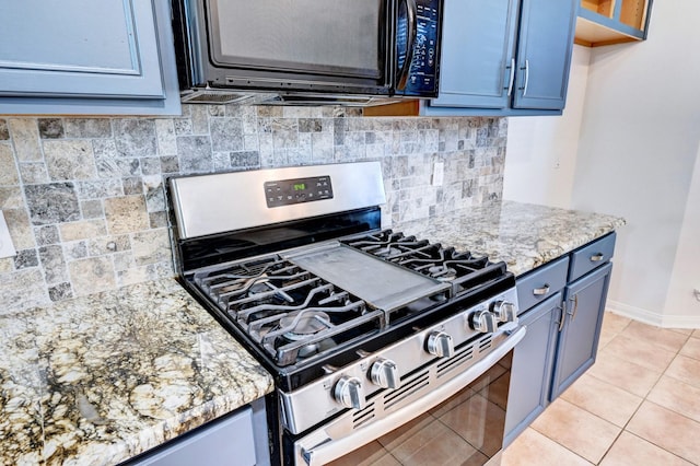 kitchen featuring blue cabinetry, gas stove, tasteful backsplash, light tile patterned floors, and light stone countertops