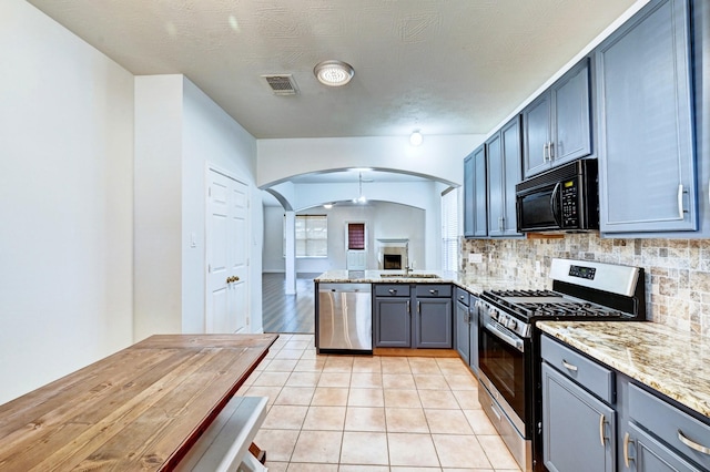 kitchen with tasteful backsplash, light stone countertops, appliances with stainless steel finishes, and light tile patterned floors