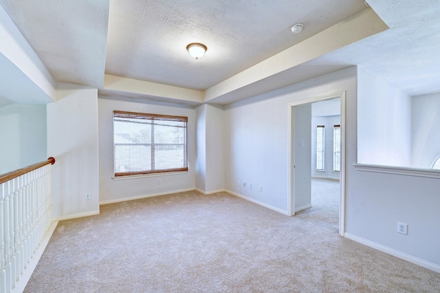 empty room featuring a wealth of natural light, light colored carpet, and a raised ceiling