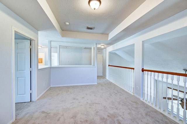 hall featuring light carpet and a textured ceiling