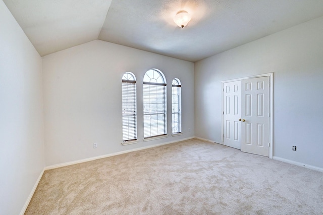 carpeted empty room featuring lofted ceiling