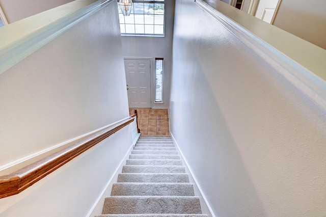 stairs with a towering ceiling and carpet