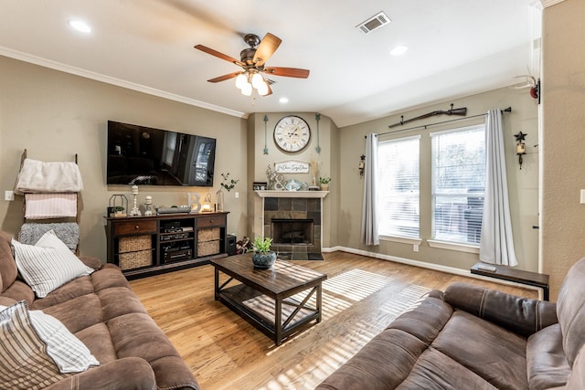 living room with crown molding, ceiling fan, a fireplace, and light hardwood / wood-style floors