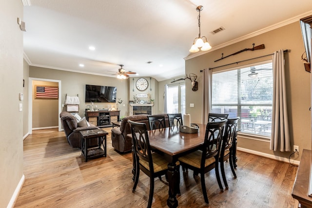 dining space featuring ceiling fan with notable chandelier, ornamental molding, and light hardwood / wood-style floors