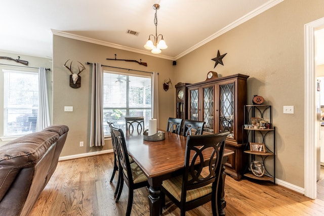 dining room with an inviting chandelier, crown molding, and light hardwood / wood-style flooring