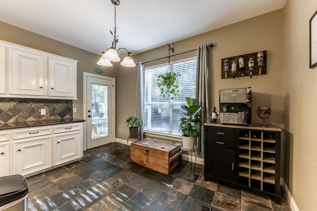 kitchen featuring white cabinetry, backsplash, and decorative light fixtures