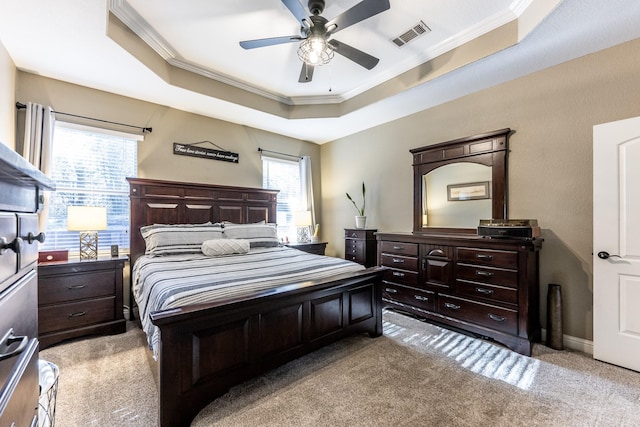 carpeted bedroom with ornamental molding, ceiling fan, and a tray ceiling