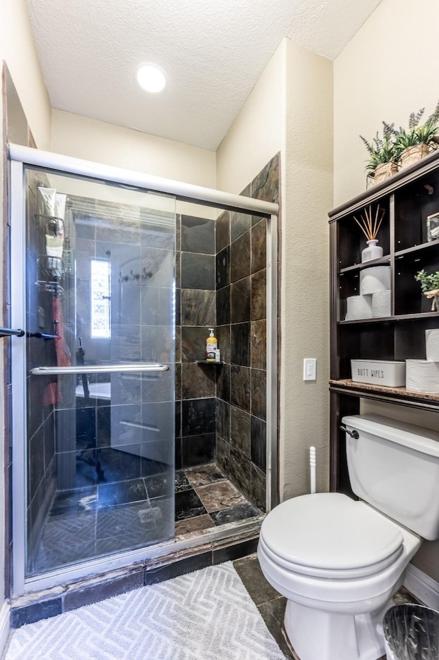 bathroom featuring toilet, an enclosed shower, and a textured ceiling