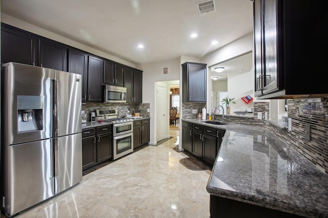 kitchen featuring dark stone countertops, sink, backsplash, and stainless steel appliances