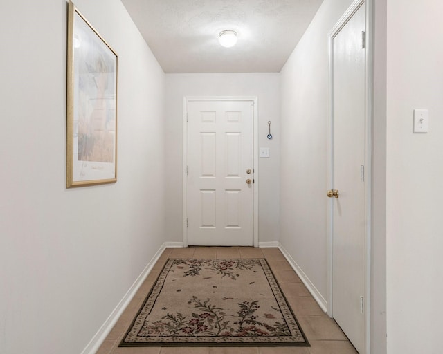 doorway featuring light tile patterned flooring and a textured ceiling