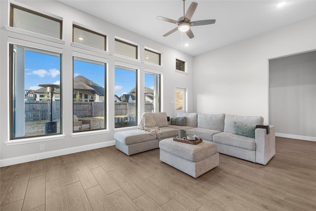 living room featuring a high ceiling, ceiling fan, and light hardwood / wood-style floors