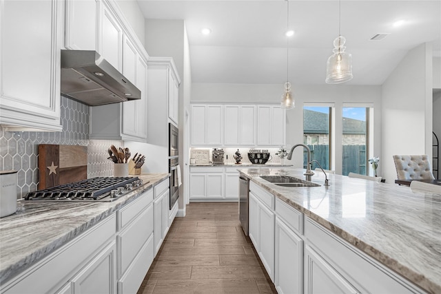 kitchen featuring sink, white cabinets, hanging light fixtures, stainless steel appliances, and light stone countertops