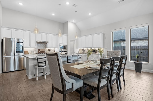 dining area with dark hardwood / wood-style floors and high vaulted ceiling